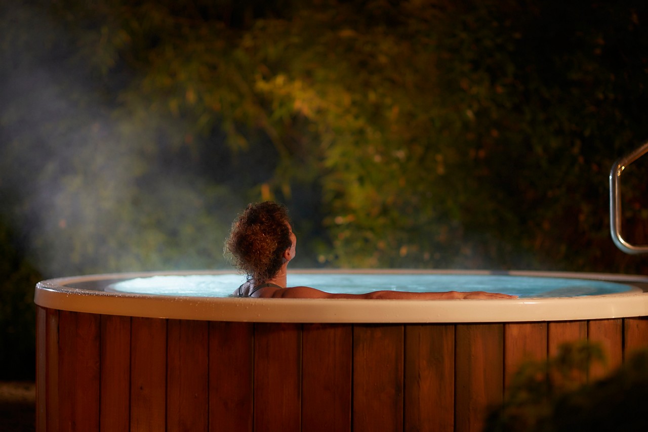 Woman soaking in a steamy outdoor hot tub.